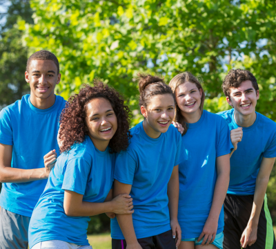 A smiling group of teenagers in blue t-shirts
